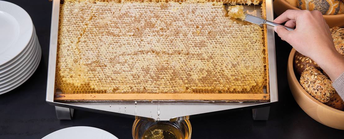 Ospite che preleva miele e favo dal dispenser con un coltello