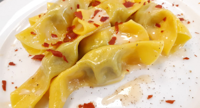 Candies shape pasta filled with nettle paste, parmigiano reggiano and crispy prosciutto