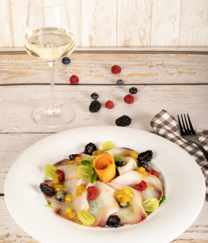 Carpaccio d'espadon avec mesclun, chutney mangue et poivre rose et fruits rouges frais – décorer avec de la menthe
