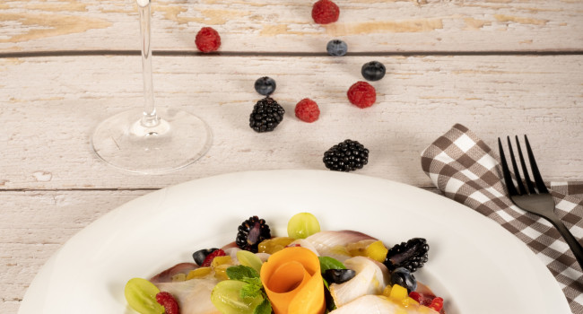 Carpaccio d'espadon avec mesclun, chutney mangue et poivre rose et fruits rouges frais – décorer avec de la menthe