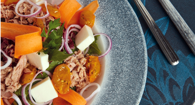 Ensalada de atún con tomates dátil amarillos, cebollas cortadas en rodajas y mozzarella