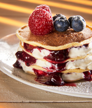 Pancake with wild berry topping, whipped cream and fresh red berries
