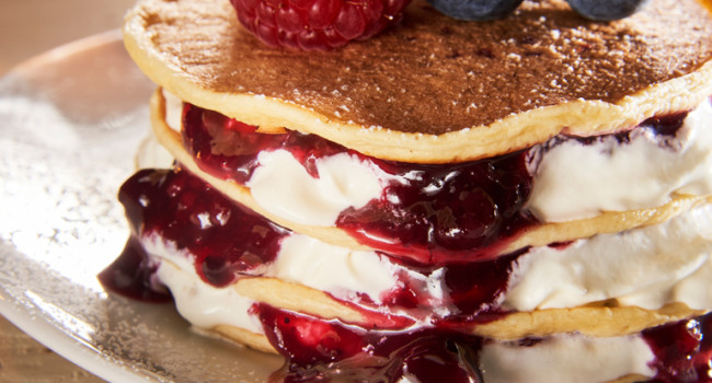 Pancake with wild berry topping, whipped cream and fresh red berries