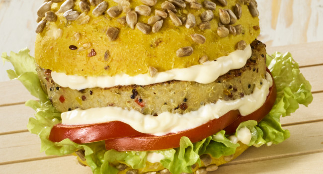 Bocadillo de pan de cúrcuma con hamburguesa de quinua y verduras cortadas en dados, con mayonesa vegana