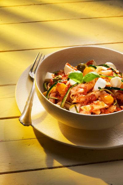Gluten-Free Penne with red pesto, baby mozzarellas, Castelvetrano olives, yellow “Datterini” tomatoes, julienned courgettes and prawns