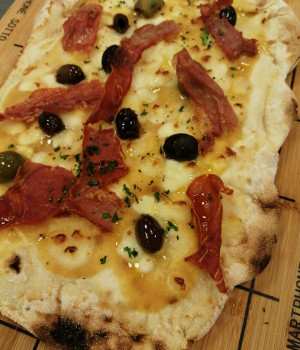 Pizza P.A.L.A. con pomodori pelati gialli, mozzarella di bufala, tris di olive piccanti e bacon