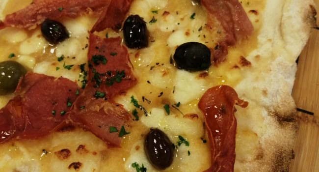 Pizza P.A.L.A. con pomodori pelati gialli, mozzarella di bufala, tris di olive piccanti e bacon
